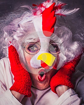 What is it? Female portrait in a chicken mask. Emotional facial expression