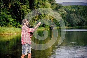 What a fish. mature bearded man with fish on rod. big game fishing. relax on nature. hipster fishing with spoon-bait