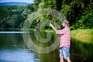 What a fish. mature bearded man with fish on rod. big game fishing. relax on nature. hipster fishing with spoon-bait