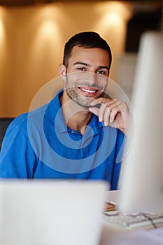 What a friendly face. Portrait of a smiling young man sitting at his desk.