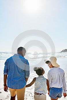 What a great day to get out with the family. an adorable little girl going for a walk with her parents on the beach.