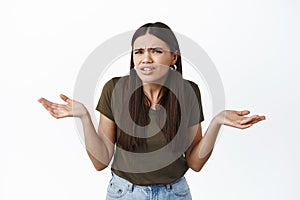 What I dont understand. Confused brunette woman staring puzzled at camera, shrugging and spread hands sideways clueless photo