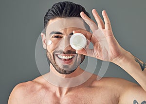 This is what I use to prevent breakouts. Studio shot of a handsome young man holding up a skincare product.