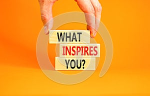 What inspires you symbol. Concept words What inspires you on wooden block. Beautiful orange table orange background. Businessman