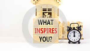 What inspires you symbol. Concept words What inspires you on wooden block. Beautiful white table white background. Black alarm