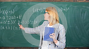 What makes great teacher. Teacher smart woman with book explain topic near chalkboard. School teacher explain things