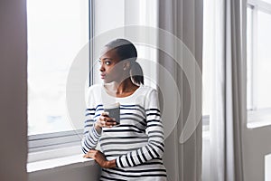 What are the neighbours up to now. A thoughtful young woman gazing out of a window on her coffee break.