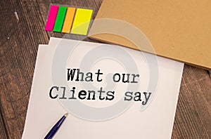 What Our Clients Say statement on paper note pad. Office desk with electronic devices