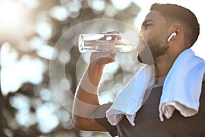 What a refreshing run outdoors. Low angle shot of a sporty young man drinking water while exercising outdoors.