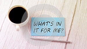 WHAT`S IN IT FOR ME text on the blue sticker with cofee and pen