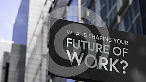What`s Shaping Your Future of Work? on a black city-center sign in front of a modern office building