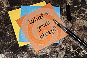 What`s your story, a question mark, a note on an orange sticker lying on a marble table