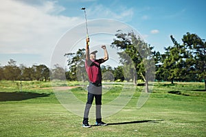 What a shot. a cheerful young male golfer lifting up his hands in success of playing a good shot outside during the day.