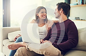 What should we do next. a cheerful young couple using a laptop while relaxing on the sofa together at home.