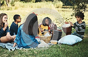 What song should we play next. Shot of a group of teenagers playing musical instruments in nature at summer camp.