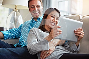 What weekends are for. a happy young couple relaxing and using a digital tablet together on the sofa at home.