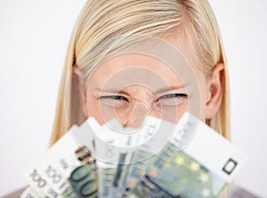 What a windfall. An excited young woman looking at her cash with scrunched eyelids.