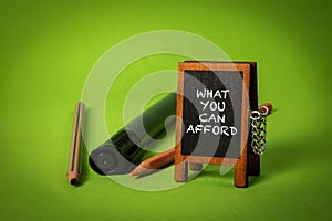 What You Can Afford. Miniature chalkboard with text. Green backgroun