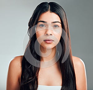 What are you doing to your hair. Studio shot of a beautiful young woman with half curled hair and half straight.