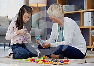 What are you making. Shot of a girl and her grandmother playing with toys at home.