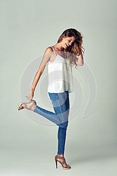 Whatever you wear today, wear it well. Studio shot of a beautiful young woman getting undressed against a gray