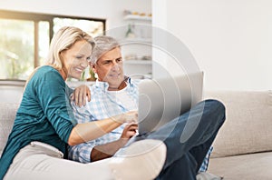 Whats that. an affectionate mature couple using a laptop while sitting on the sofa together at home.