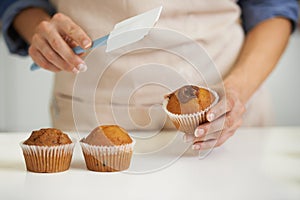 Whats a cupcake without some frosting. A closeup image of a woman applying frosting to a cupcake.