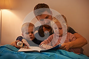 Whats that, Daddy. A father reading a bedtime story to his kids.