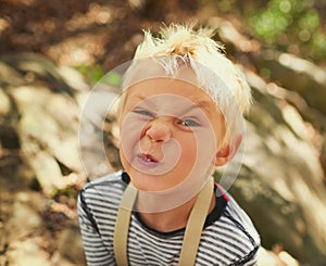 Whats the funniest face you can pull. Portrait of an adorable little boy playing outdoors.