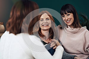 Whats the latest gossip. three middle aged women having a chat together at home during the day.