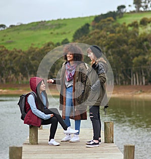 Whats said on the pier, stays on the pier. a group of friends having a conversation on a pier by a lake.