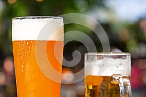 A wheat beer and a pils are standing on a table in a beer garden