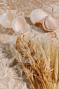 Wheat ears and flour and eggs on the background of the dough board