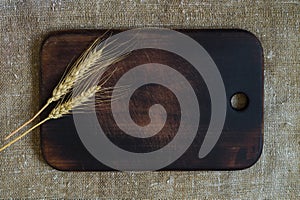 Wheat ears on a kitchen board on a sacking background