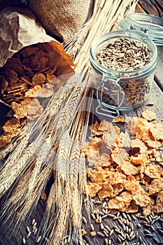 Wheat flakes, spikes and rye grain on wooden table