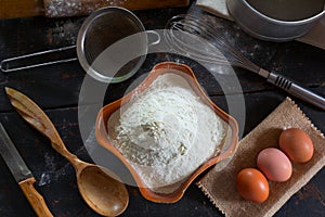 Wheat flour in a ceramic dish and chicken eggs for the dough preparation