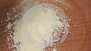 Wheat flour is falls into glass dish, slow motion. Closeup