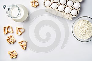 Wheat flour in the glass bowl, cream in a glass jar, chicken eggs - ingredients for the dough, top view