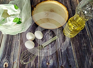 Wheat flour, milk, chicken eggs, vegetable oil, frying pan and whisk for whisking on a wooden table