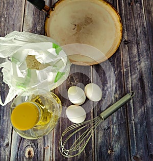 Wheat flour, milk, chicken eggs, vegetable oil, frying pan and whisk for whisking on a wooden table