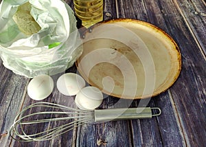 Wheat flour, milk, chicken eggs, vegetable oil, frying pan and whisk for whisking on a wooden table