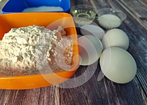 Wheat flour, milk, chicken eggs, vegetable oil, salt and sugar on a wooden table.  Ingredients for fried pancakes