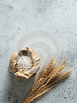 Wheat flour in paper bag on gray cement background
