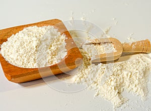 wheat flour powder  on a wooden bowl and  rustic wooden scoop  on white background