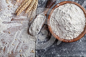 Wheat flour with scoop and wheat ears on kitchen board top view. Ingredient for baking photo