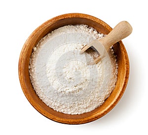 Wheat flour in a wooden bowl with a scoop on a white background. Isolated, top view