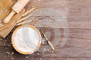 wheat flour in a wooden bowl There are ears of wheat on the table. Old wooden background - top view