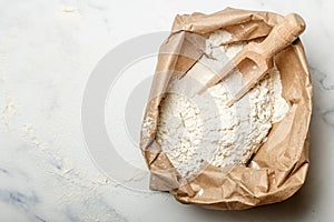 Wheat flour and a wooden scoop in a paper bag