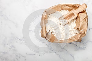 Wheat flour and a wooden scoop in a paper bag