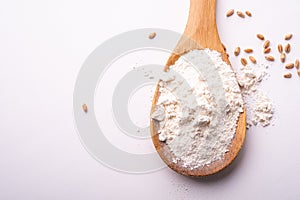 Wheat flour in wooden spoon spatula near with heap of grains, top view, flat lay, isolated on white background